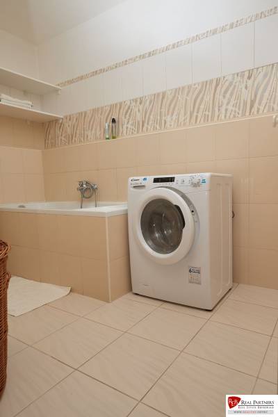 Badezimmer mit Badewanne, Waschmaschine und Regal in einer 2-Zimmer-Wohnung.