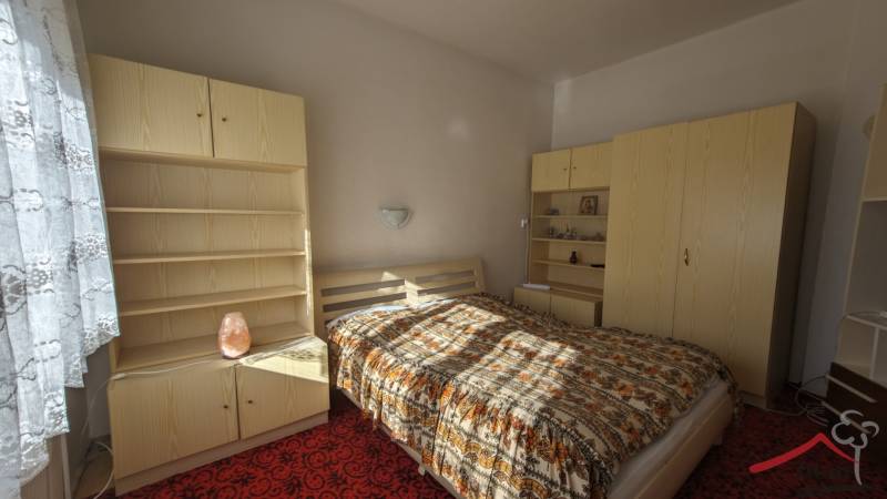 Ein Schlafzimmer in einem Einfamilienhaus mit hellen Möbeln und gemustertem Bettüberwurf.