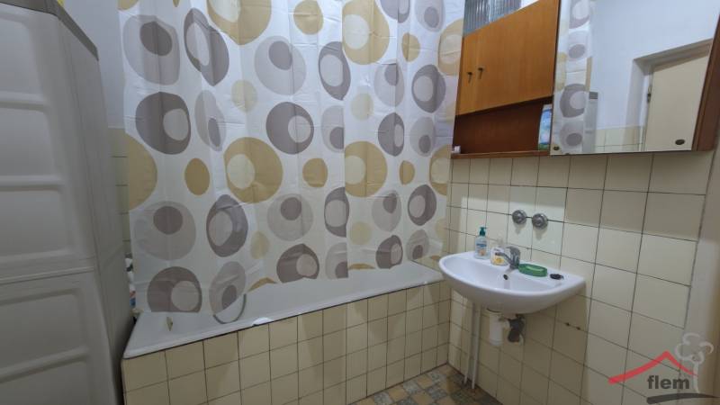 Badezimmer in einem Einfamilienhaus, Badewanne mit Vorhang, Waschbecken mit Seife und Spiegel.