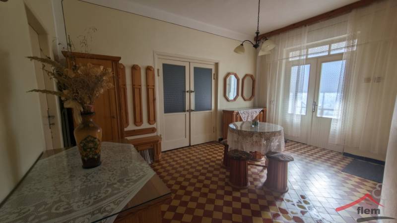 Innenraum eines Einfamilienhauses mit farbigen Fliesen, einer Blumenvase und Vorhängen.