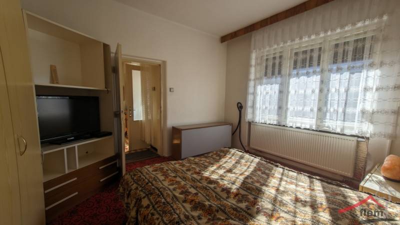 Ein Schlafzimmer in einem Einfamilienhaus mit einem Fernseher und Bettwäsche mit Blumenmuster.