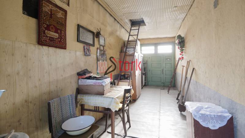 Innenraum eines Einfamilienhauses mit einer Leiter neben einer bestickten Tapisserie. Boden mit Holzdekor.