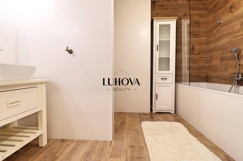 Badezimmer mit weißen Fliesen und Boden in Holzoptik in einer 3-Zimmer-Wohnung.