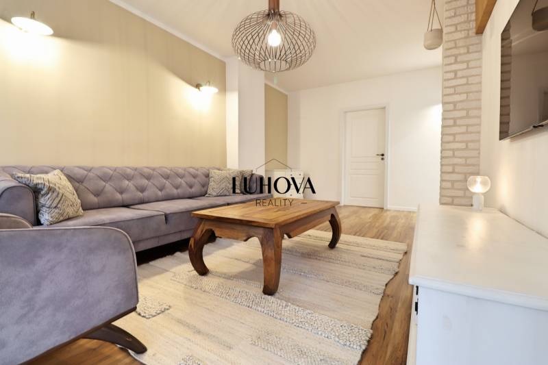 Wohnzimmer in einer 3-Zimmer-Wohnung mit Sofa, Holztisch und Boden mit Holzdekor.