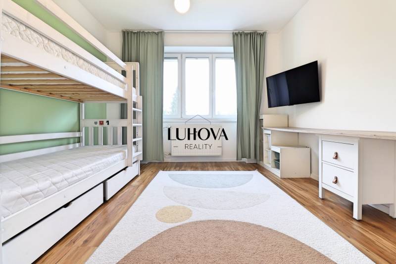 Ein Zimmer in einer 3-Zimmer-Wohnung mit einem Etagenbett, einem Fernseher und einem Boden in Holzoptik.