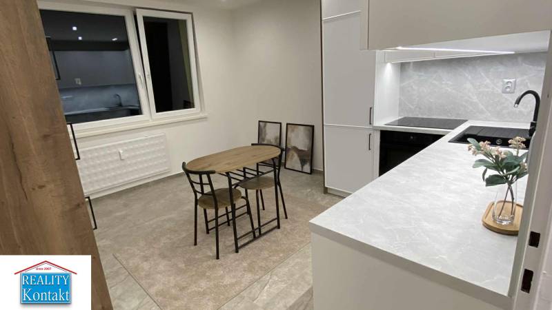 Küche in einer Einzimmerwohnung mit Esstisch, Schränken und dekorativen Bildern an der Wand.