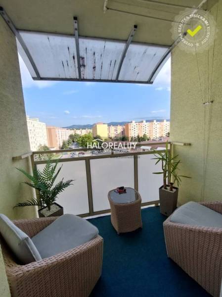 Balkon einer 3-Zimmer-Wohnung mit Rattanmöbeln und Blick auf die Siedlung in Prievidza.