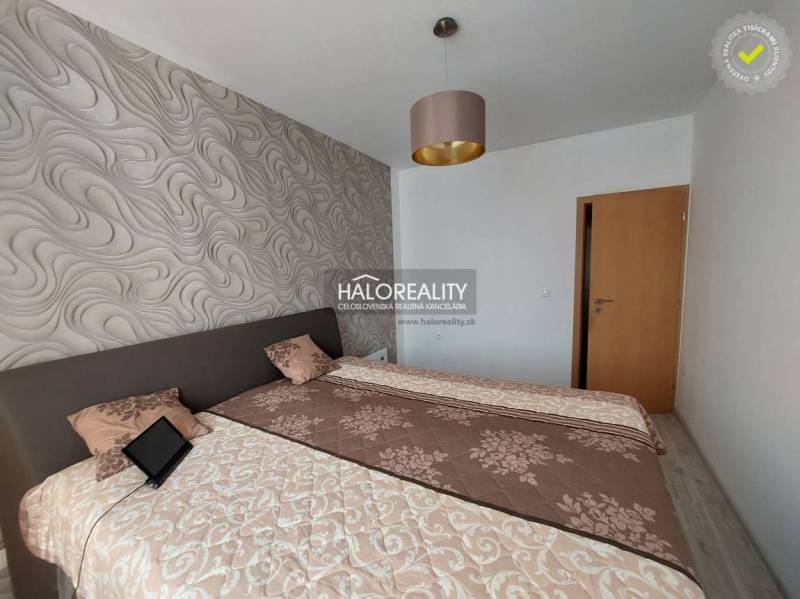 Schlafzimmer in einer 3-Zimmer-Wohnung mit gemusterten Tapeten und Betten mit Decken.