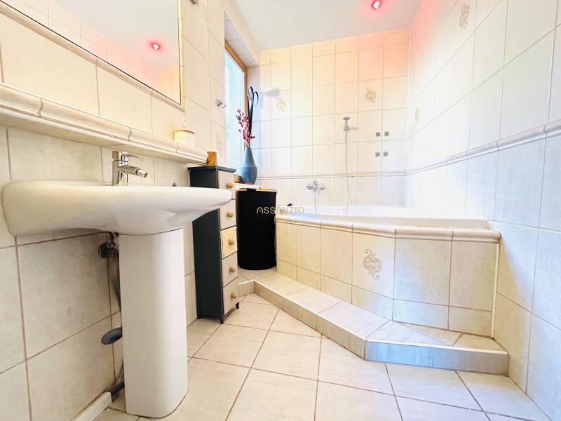 Badezimmer mit Badewanne, Waschbecken und Fliesen in einer 2-Zimmer-Wohnung.