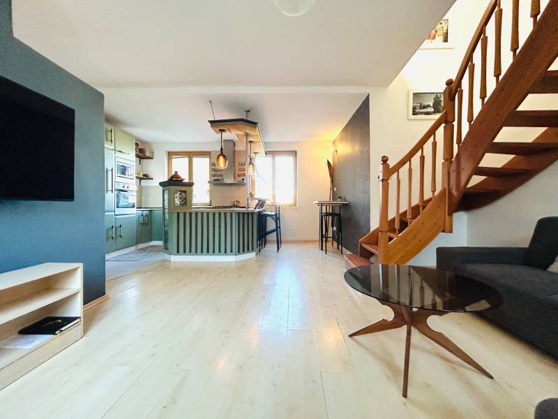 Wohnzimmer in einer 2-Zimmer-Wohnung mit Küche und Treppe, Boden mit Holzdekor.