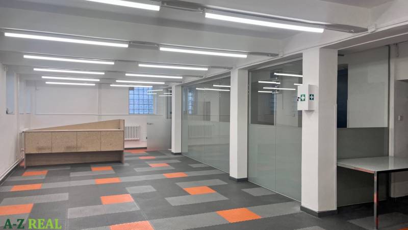 Gewerbeflächen mit verglasten Wänden und gemustertem Boden in Holzoptik.