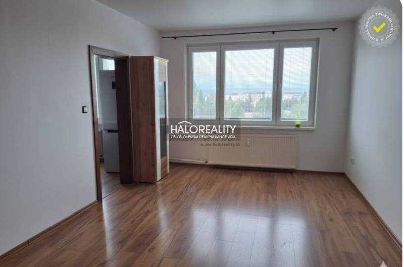 Ein Zimmer mit Holzboden und großen Fenstern in einer 3-Zimmer-Wohnung.