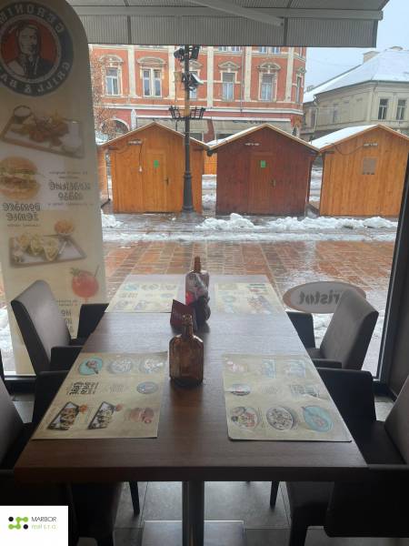 Winterlandschaft durch das Fenster eines Gastronomiebereichs mit Blick auf Holztische.