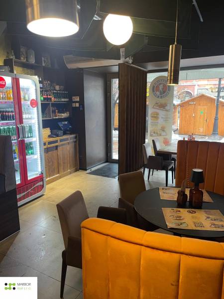 Innenraum von Gastronomiebereichen mit rundem Tisch, Stühlen und Beleuchtung.