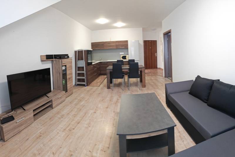 Wohnzimmer in einer 3-Zimmer-Wohnung mit Holzboden, Kochnische und Sofa.