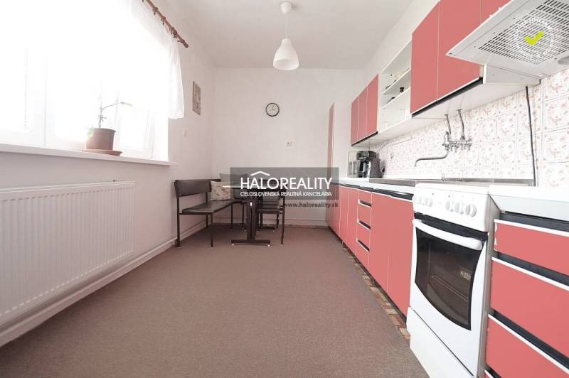 Eine Küche in einem Einfamilienhaus mit roten Schränken und einem Essbereich.