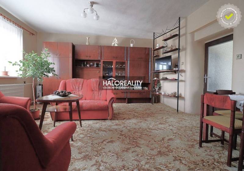 Wohnzimmer in einem Einfamilienhaus mit Sesseln, Vitrine und Teppich.