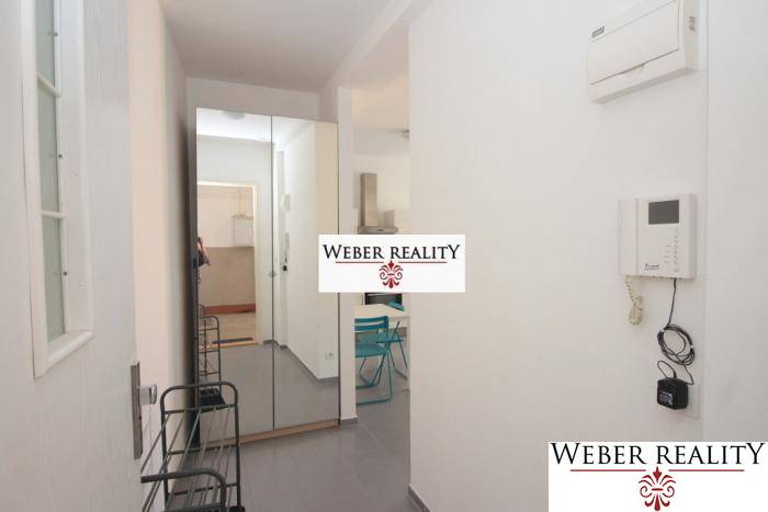 Flur in einer 2-Zimmer-Wohnung mit Garderobe, Spiegel und Fliesen.