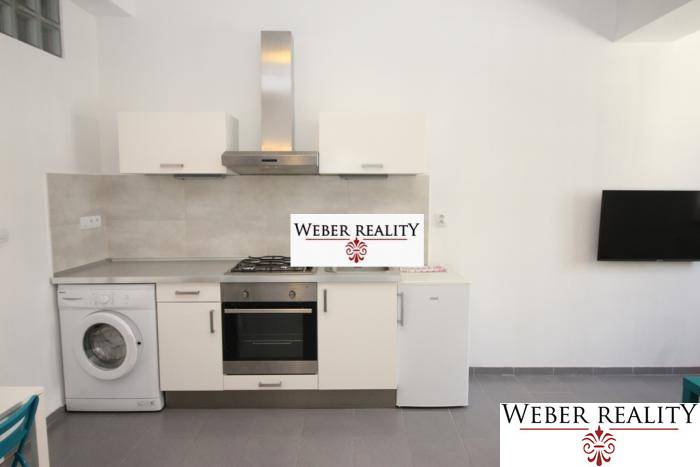 Küche in einer 2-Zimmer-Wohnung mit Geräten und Fernseher an der Wand.