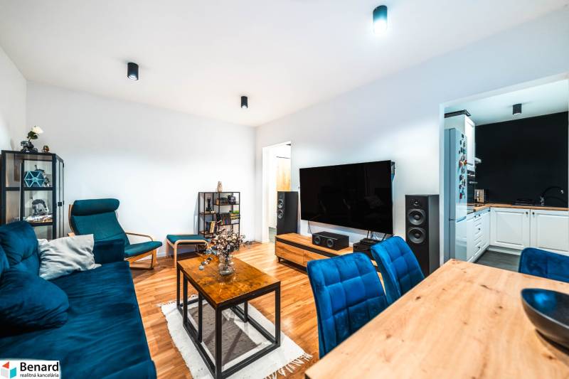 Wohnzimmer einer Zweizimmerwohnung mit Holzboden und blauen Sofas.