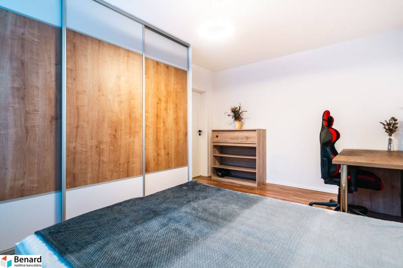 Ein Zimmer in einer 2-Zimmer-Wohnung mit einem Boden in Holzoptik, einem Schrank und einem Schreibtisch.
