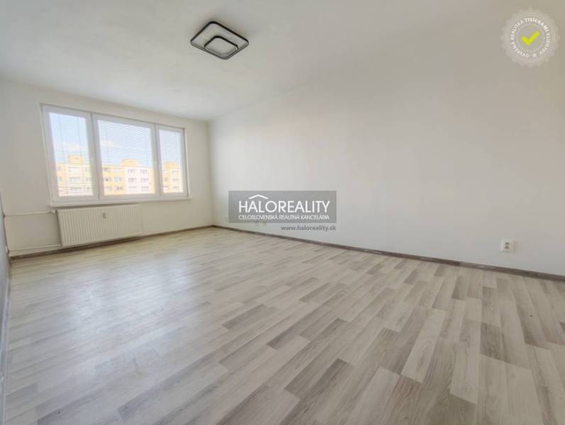 Ein Zimmer mit großen Fenstern und einem Boden in Holzoptik in einer 2-Zimmer-Wohnung.