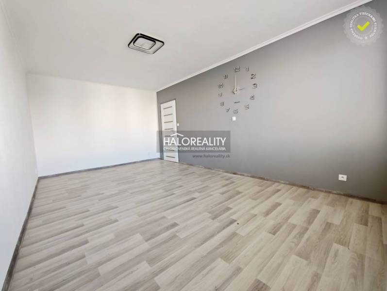 Ein Zimmer mit einer Uhr und einem Boden in Holzoptik in einer 2-Zimmer-Wohnung.