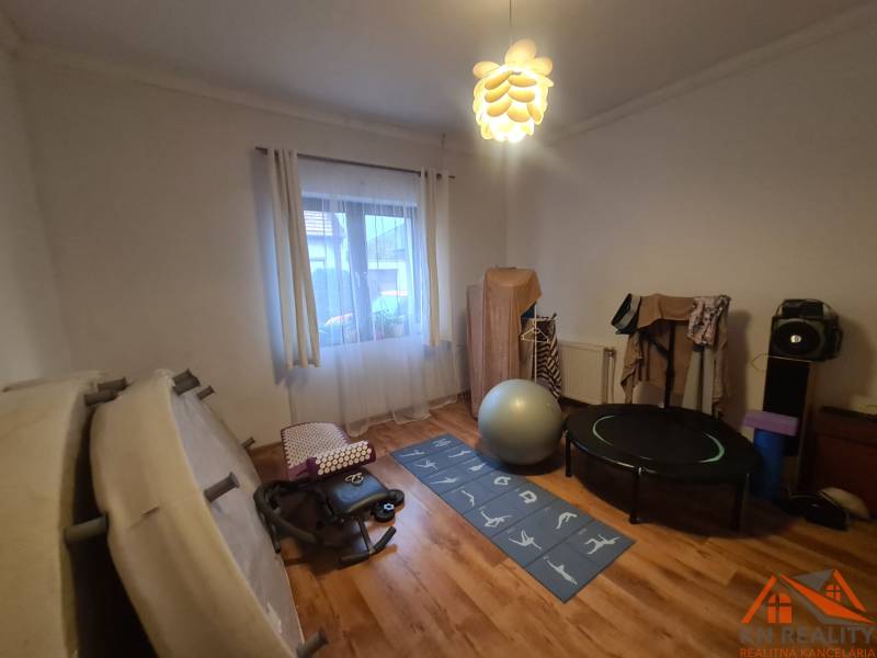 Fitnessstudio im Einfamilienhaus mit Trainingsgeräten und Boden in Holzoptik.