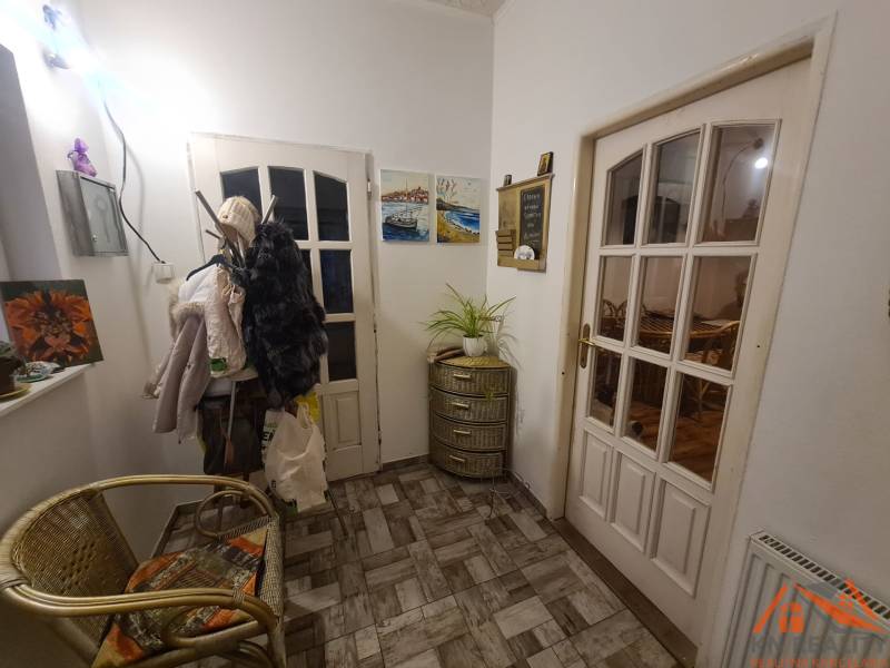 Der Flur eines Einfamilienhauses mit einem Sessel, Wandbildern und einem Garderobenständer.