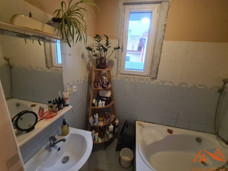 Ein Badezimmer in einem Einfamilienhaus mit einer Badewanne, einem Spiegel und einem Regal für Toilettenartikel.