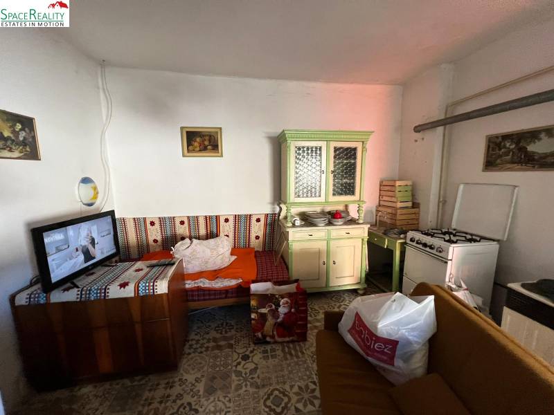 Ein Zimmer mit Sofa, Küchenzeile, Herd und Fernseher in einem Einfamilienhaus.