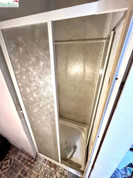 Duschkabine im Innenraum eines Einfamilienhauses mit Fliesen und dekorativem Boden.