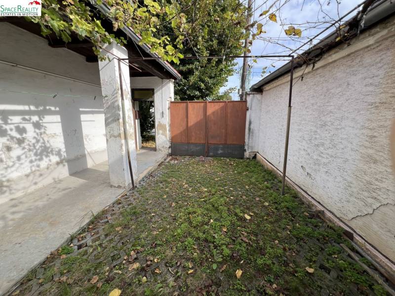 Der Hof des Einfamilienhauses in Jablonec mit Steinpflaster und Grünflächen.