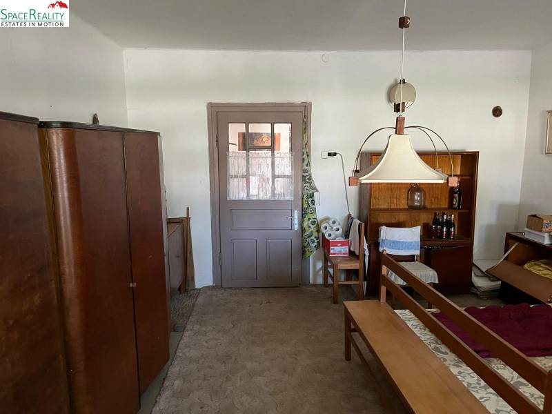 Innenraum eines Einfamilienhauses mit Möbeln und Teppich, zentrale Lampe und Regal mit Getränken.