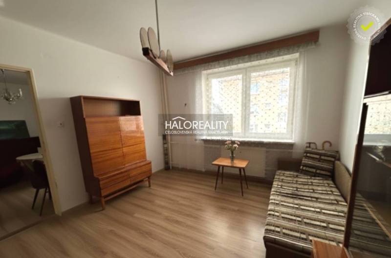 Wohnzimmer in einer 3-Zimmer-Wohnung mit Holzboden, Sofa, Schrank und Fenster.