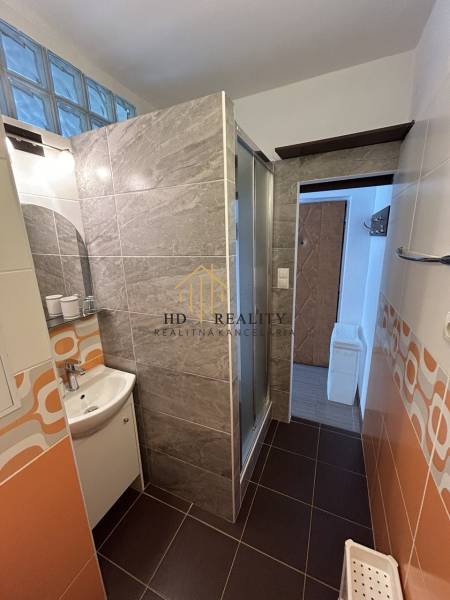 Badezimmer mit modernen Fliesen und einer Dusche in einer Einzimmerwohnung.