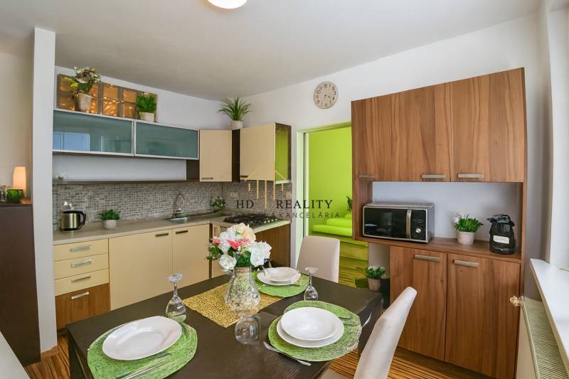 Küche in einer Einzimmerwohnung mit Esstisch und Boden in Holzoptik.