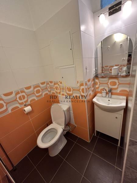 Badezimmer in einer Einzimmerwohnung mit orangefarbenen Fliesen und Waschbecken.