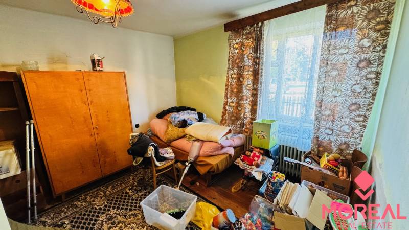 Ein Raum im Einfamilienhaus mit Unordnung, alten Möbeln und einem Ausblick durch das Fenster.