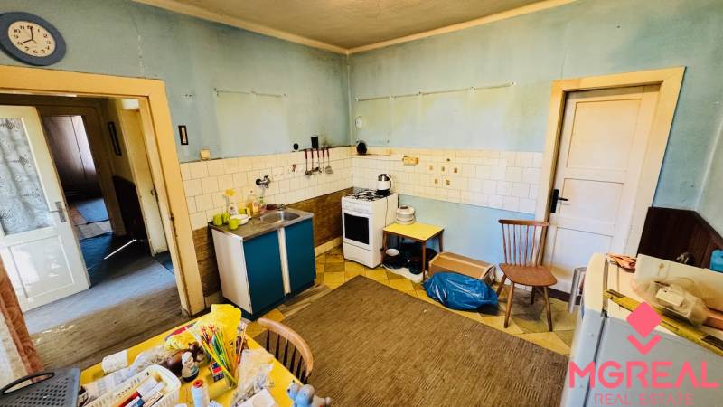 Eine Küche in einem Einfamilienhaus mit blauen Wänden, älteren Möbeln und praktischer Ausstattung.