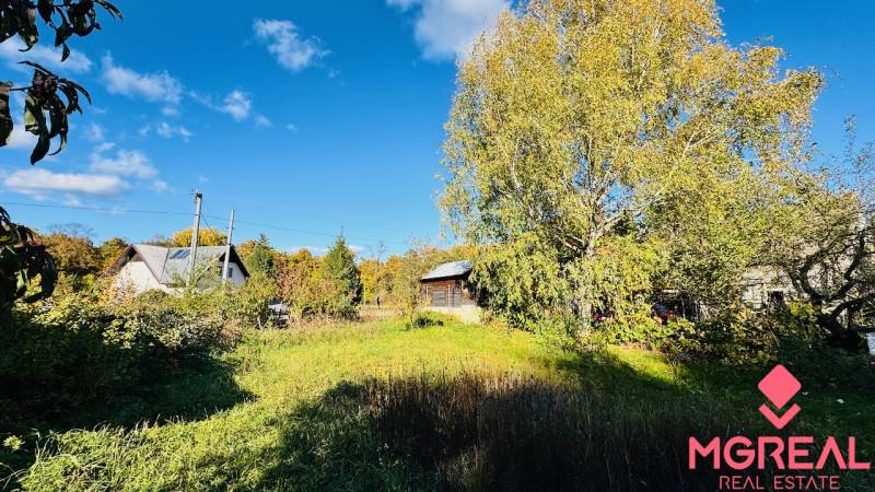 Ein Einfamilienhaus in Brodzany in einem Garten mit weitläufigem Rasen und Bäumen unter blauem Himmel.