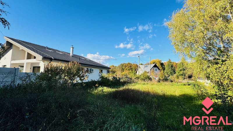 Ein Einfamilienhaus in Brodzany, umgeben von Grün und klarem blauen Himmel.