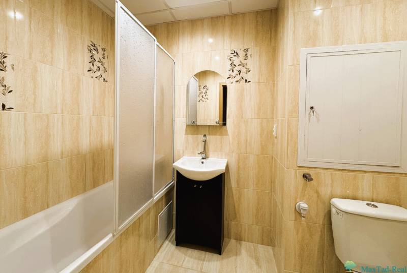 Badezimmer mit Badewanne, Waschbecken und Toilette in einer 3-Zimmer-Wohnung mit hellen Fliesen.