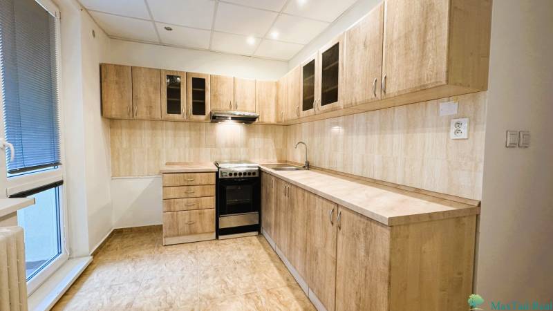 Küche in einer 3-Zimmer-Wohnung mit Holzdekor-Schränken und Fliesenboden.