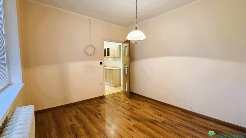 Ein Zimmer in einer 3-Zimmer-Wohnung mit einem Boden in Holzoptik, Blick in die Küche.