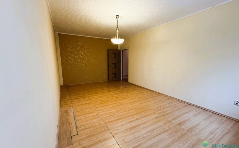 Wohnzimmer mit Holzboden, Kronleuchter und gemusterter Wand in einer 3-Zimmer-Wohnung.