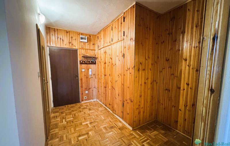 Ein Flur mit holzverkleideten Wänden und einem Boden in Holzoptik in einer 3-Zimmer-Wohnung.