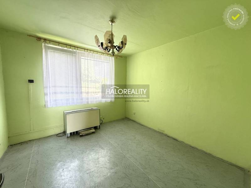 Ein Zimmer mit einem Kronleuchter, einem Fenster und einem Heizkörper in einer 3-Zimmer-Wohnung.