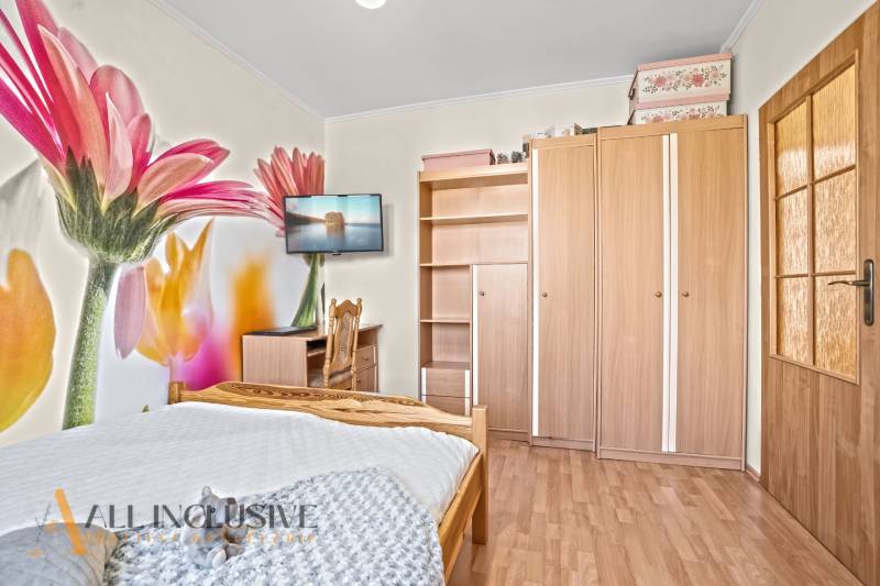 Ein Schlafzimmer in einem Einfamilienhaus mit einer Blumentapete, einem Holzboden und Möbeln.