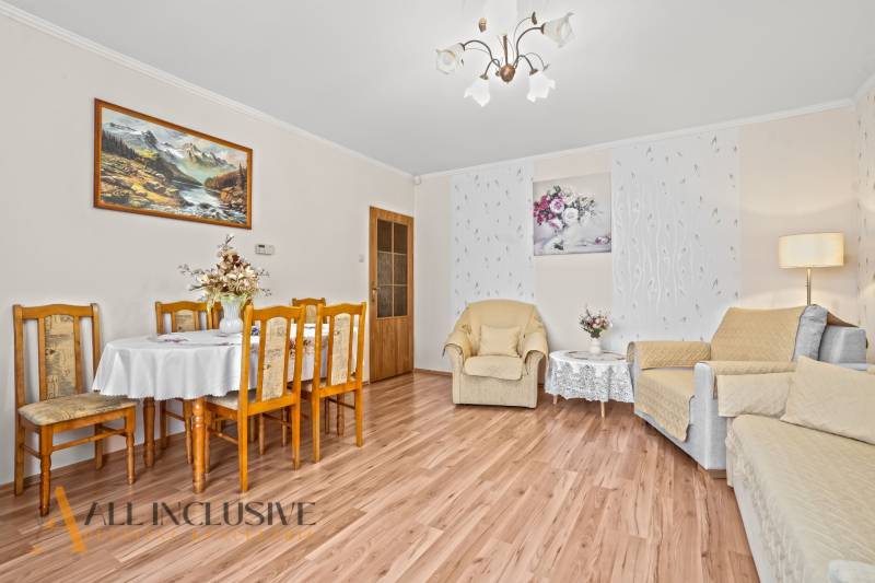 Wohnzimmer in einem Einfamilienhaus, Boden mit Holzdekor, Esstisch, Sessel, Bilder.